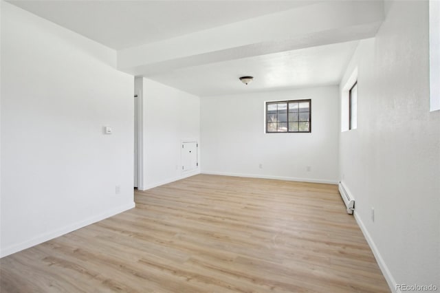 empty room with light wood-style flooring, a baseboard heating unit, and baseboards