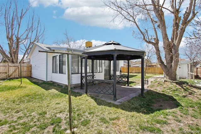 back of house with a gazebo, a patio area, a fenced backyard, and a lawn