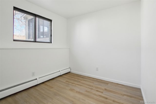 spare room with baseboards, light wood-type flooring, and baseboard heating