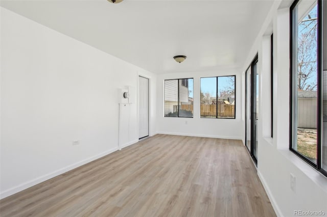 empty room featuring light wood-style flooring, a wealth of natural light, and baseboards