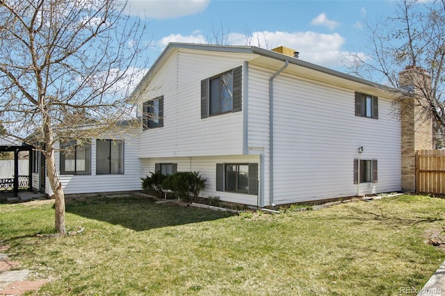 back of house featuring fence, a yard, a gazebo, and a chimney
