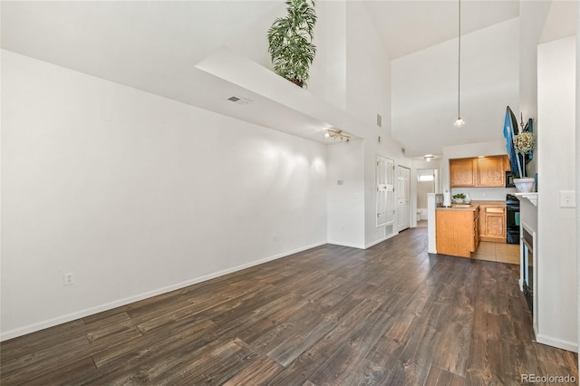 kitchen with black range with electric stovetop, decorative light fixtures, dark hardwood / wood-style floors, and a high ceiling