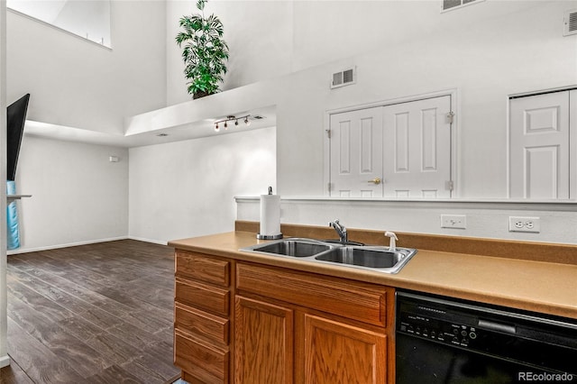 kitchen featuring a high ceiling, black dishwasher, sink, and dark wood-type flooring