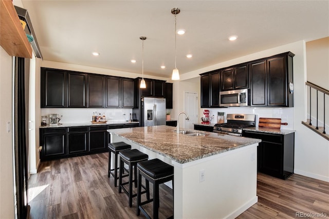 kitchen featuring pendant lighting, appliances with stainless steel finishes, sink, a kitchen island with sink, and hardwood / wood-style flooring