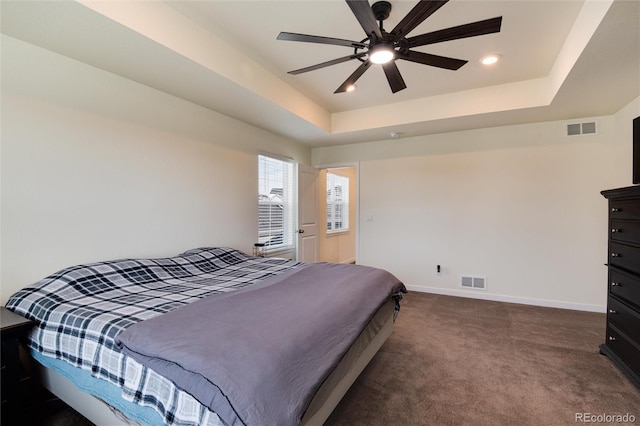 bedroom with ceiling fan, carpet floors, and a tray ceiling