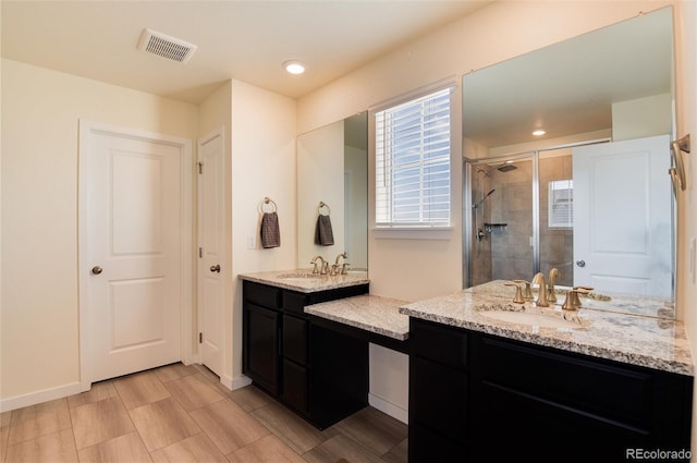 bathroom featuring a shower with door and vanity