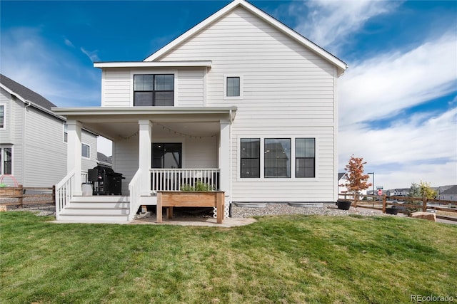 back of property with covered porch and a yard