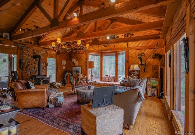 living room featuring light hardwood / wood-style floors, lofted ceiling with beams, wood walls, a wood stove, and wooden ceiling