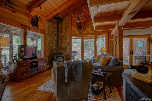 living room with hardwood / wood-style flooring, wooden ceiling, a wood stove, and a wealth of natural light