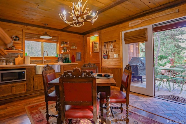 dining area with an inviting chandelier, a healthy amount of sunlight, sink, and hardwood / wood-style flooring