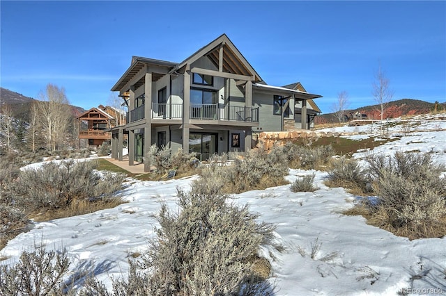 snow covered house featuring a balcony