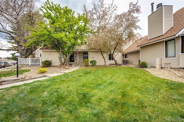 exterior space featuring a lawn, central air condition unit, a chimney, and a shingled roof