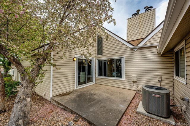 rear view of property with cooling unit, a patio, and a chimney