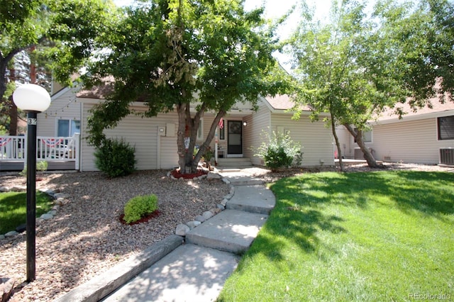 view of property hidden behind natural elements featuring a front yard and cooling unit