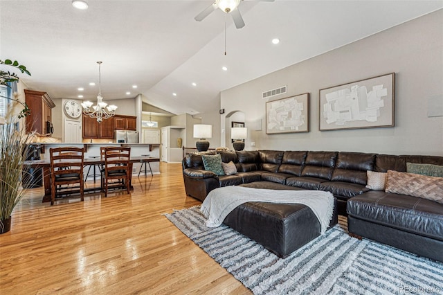 living room featuring ceiling fan with notable chandelier, light hardwood / wood-style flooring, and high vaulted ceiling