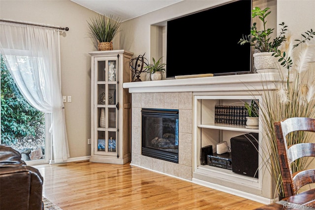 living room with wood-type flooring, a tiled fireplace, and a wealth of natural light