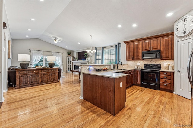 kitchen featuring light wood-type flooring, kitchen peninsula, lofted ceiling, and black appliances