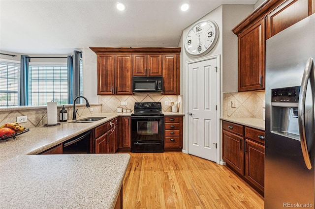 kitchen with light hardwood / wood-style floors, sink, tasteful backsplash, and black appliances