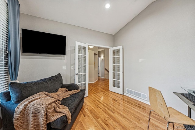 sitting room with wood-type flooring, lofted ceiling, and french doors