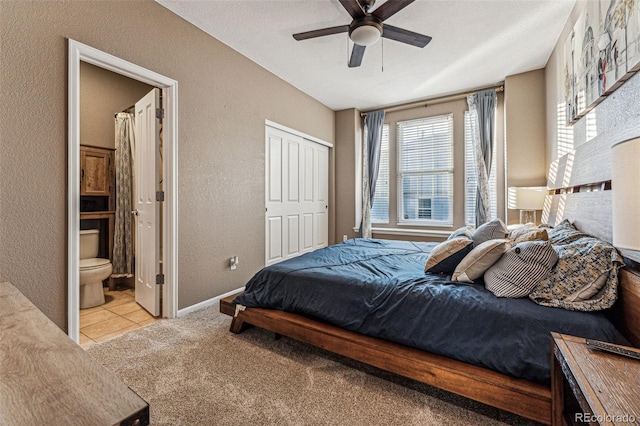 bedroom featuring light carpet, ceiling fan, ensuite bathroom, and a closet