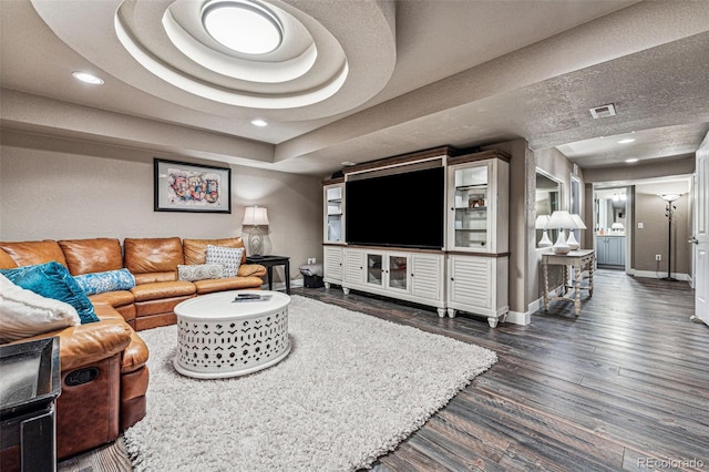 living room featuring a raised ceiling and dark hardwood / wood-style flooring