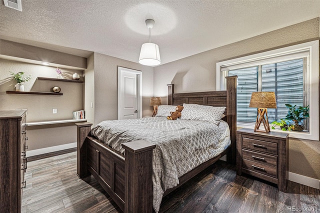 bedroom with a textured ceiling and dark wood-type flooring