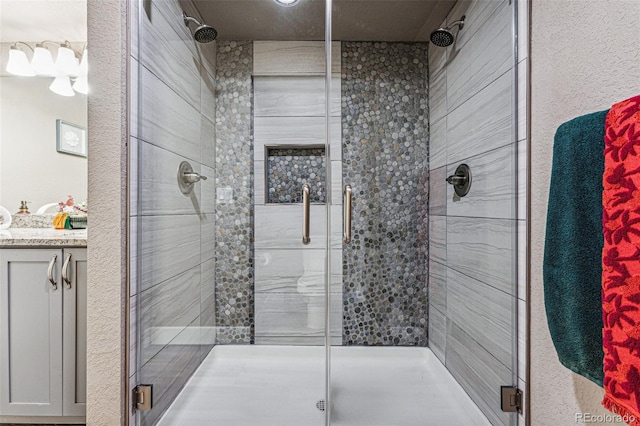 bathroom featuring a shower with door and vanity