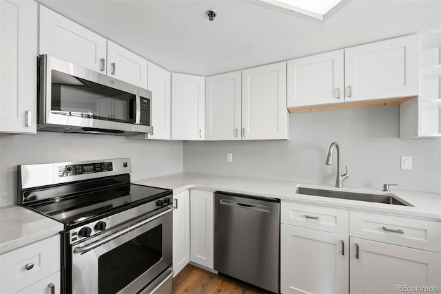 350 Detroit St Unit 107, Denver, CO 80206 - kitchen featuring light stone countertops, dark wood-style flooring, a sink, stainless steel appliances, and white cabinets