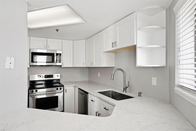 350 Detroit St Unit 107, Denver, CO 80206 - kitchen featuring a sink, open shelves, stainless steel appliances, white cabinetry, and light stone countertops
