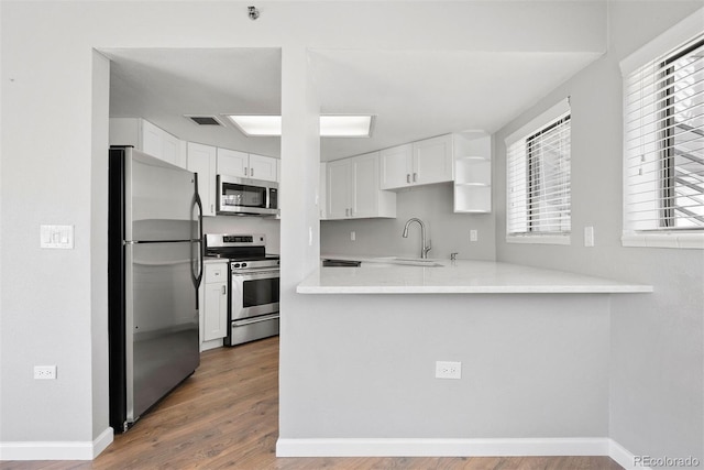 350 Detroit St Unit 107, Denver, CO 80206 - kitchen with stainless steel appliances, a sink, white cabinetry, wood finished floors, and light countertops
