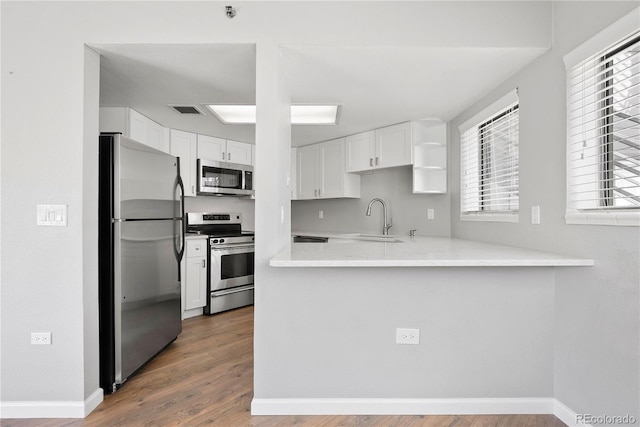 350 Detroit St Unit 107, Denver, CO 80206 - kitchen featuring stainless steel appliances, a sink, wood finished floors, light countertops, and white cabinets