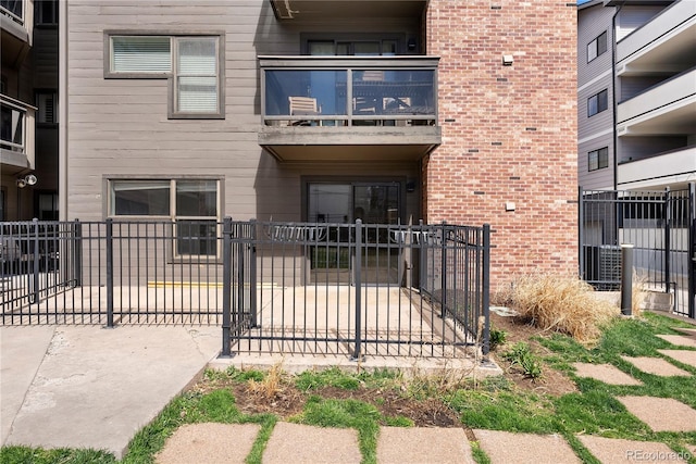 350 Detroit St Unit 107, Denver, CO 80206 - view of exterior entry featuring a balcony, brick siding, fence, and a gate