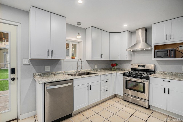 kitchen featuring stainless steel appliances, wall chimney exhaust hood, a sink, white cabinetry, and recessed lighting