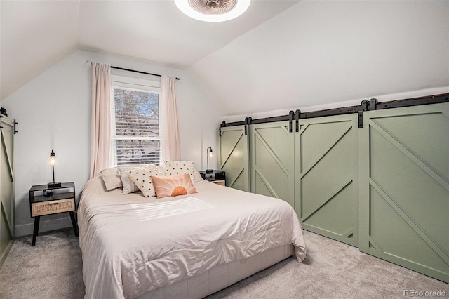 bedroom featuring light colored carpet, lofted ceiling, and a barn door