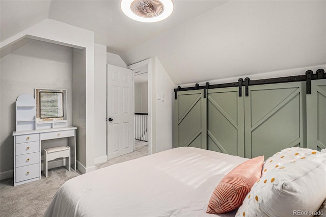 bedroom featuring light carpet, lofted ceiling, a barn door, and baseboards