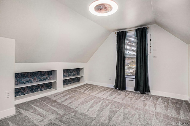 additional living space featuring built in features, vaulted ceiling, carpet flooring, and baseboards