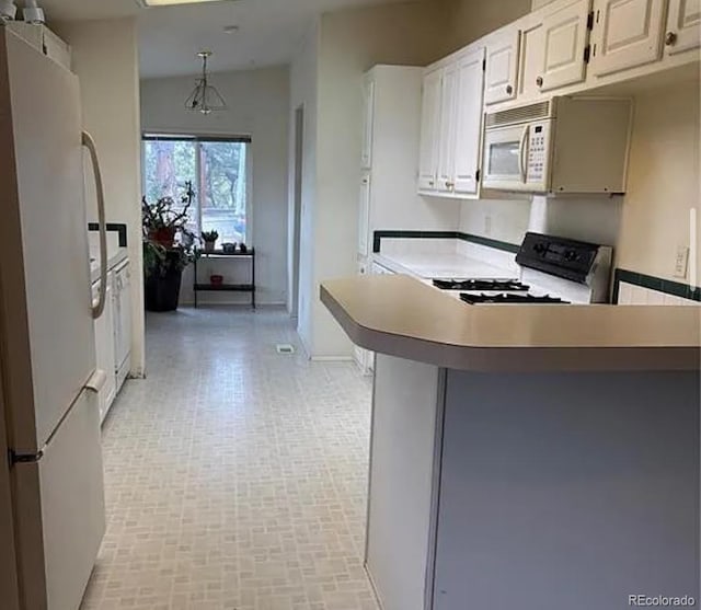 3647 Pathfinder Rd Unit B, Florissant, CO 80816 - kitchen with white appliances, a peninsula, brick patterned floors, and white cabinets