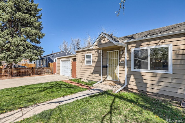 view of front of house with concrete driveway, fence, a front yard, and a garage