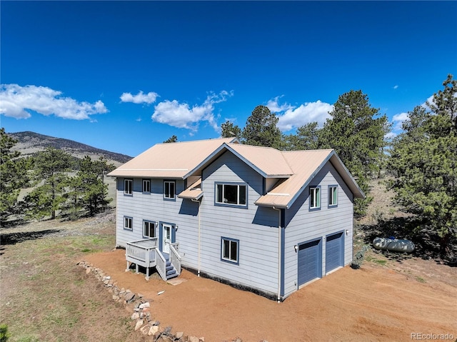 777 Deerview Dr, Florissant, CO 80816 - view of front of property featuring an attached garage, dirt driveway, metal roof, and a mountain view