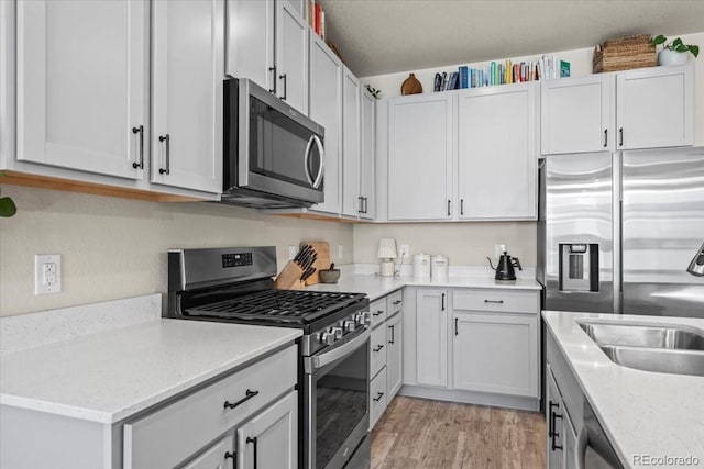 19592 W 93rd Pl Unit C, Arvada, CO 80007 - kitchen with stainless steel appliances, light wood-style flooring, light stone counters, and white cabinets