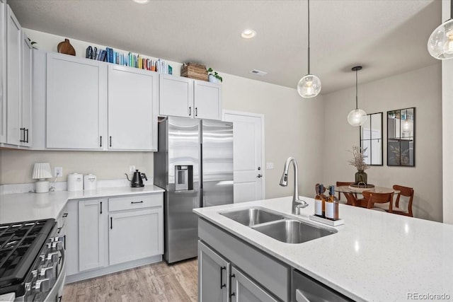 19592 W 93rd Pl Unit C, Arvada, CO 80007 - kitchen with appliances with stainless steel finishes, light wood-style flooring, pendant lighting, light stone counters, and recessed lighting