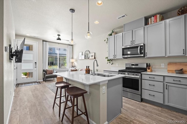 19592 W 93rd Pl Unit C, Arvada, CO 80007 - kitchen with stainless steel appliances, gray cabinets, light wood-style floors, a textured ceiling, and open floor plan