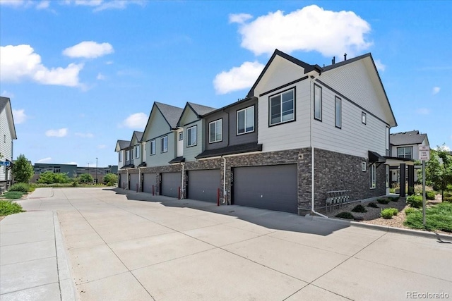19592 W 93rd Pl Unit C, Arvada, CO 80007 - view of home's exterior featuring a garage, stone siding, a residential view, and driveway
