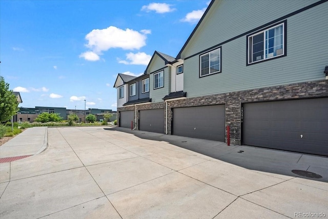 19592 W 93rd Pl Unit C, Arvada, CO 80007 - view of side of home featuring stone siding, a garage, and driveway