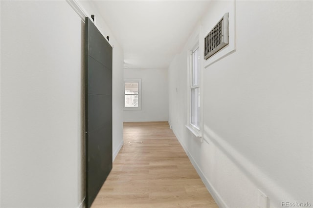 hall with a barn door and light wood-type flooring