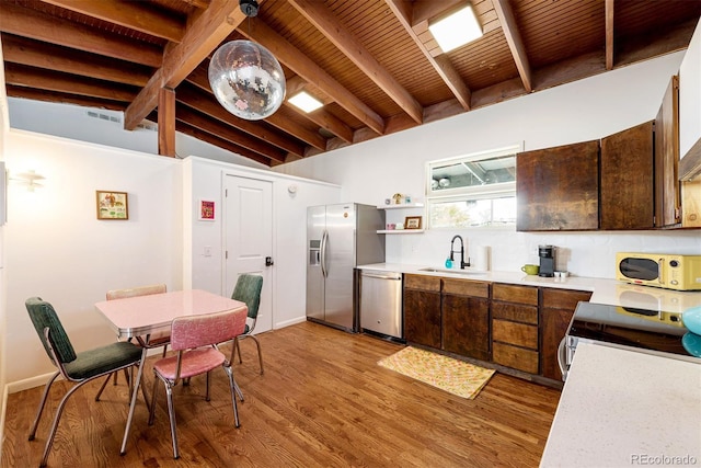 kitchen featuring light wood finished floors, a sink, stainless steel appliances, wooden ceiling, and light countertops