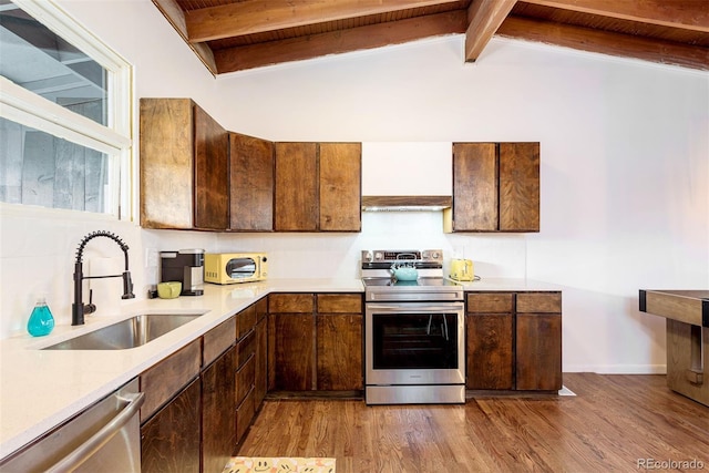 kitchen featuring a sink, stainless steel appliances, wood finished floors, and light countertops