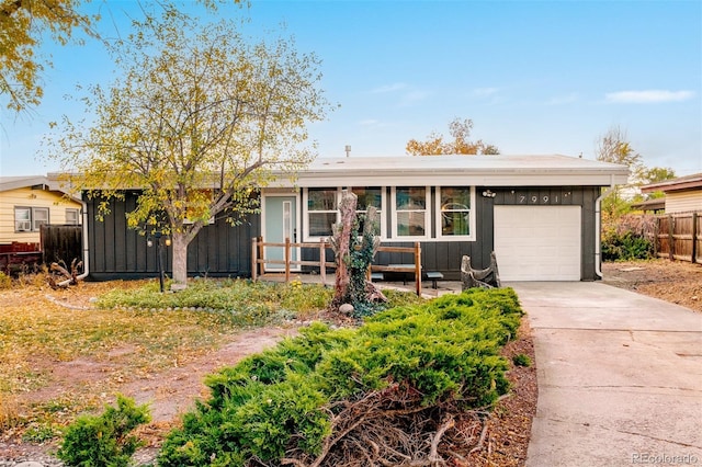 view of front of home featuring a garage, board and batten siding, concrete driveway, and fence