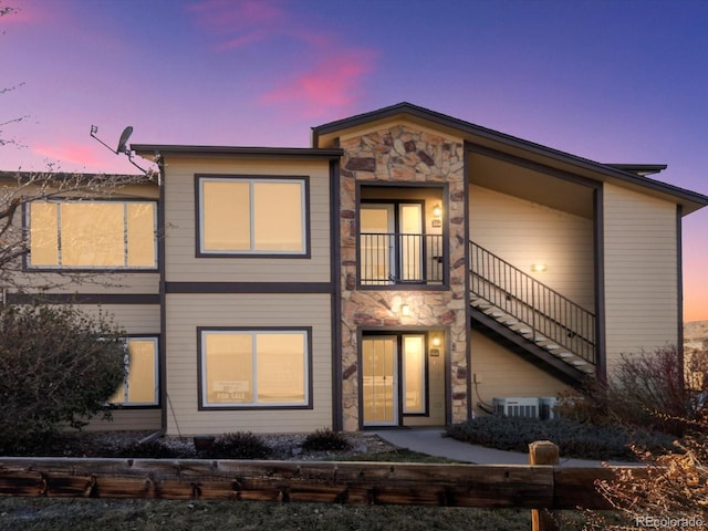 view of front of home featuring central air condition unit, stairway, and stone siding