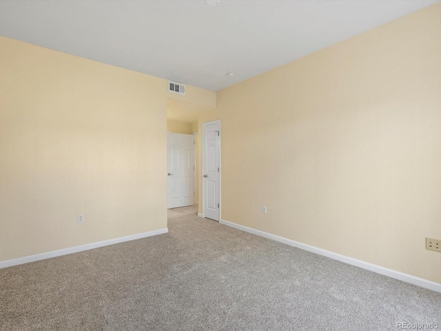 unfurnished room featuring baseboards, light carpet, and visible vents